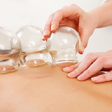 Detail of an acupuncture therapist removing a glass globe in a fire cupping procedure.jpg