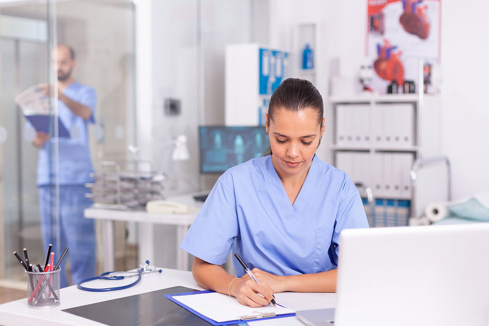 Nurse in blue scrubs writing at desk