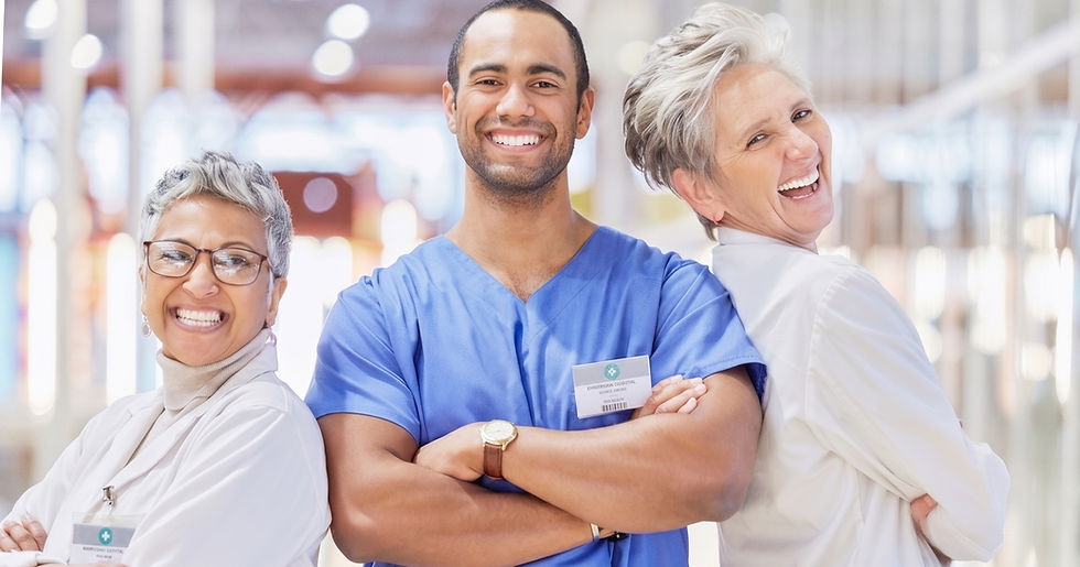 Group of five healthcare professionals, two in blue scrubs, three in white coats, smiling and posing in a bright hospital hallway.