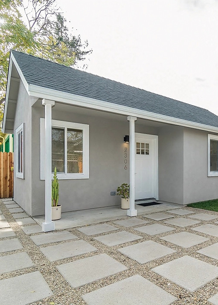 Small gray house with paved driveway and green lawn