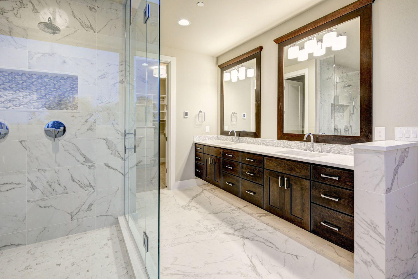 Luxury remodeled bathroom with marble tile, glass shower, and wooden cabinets