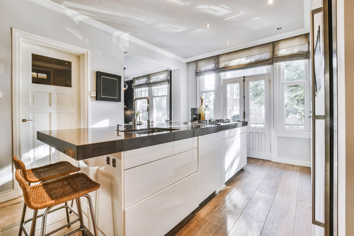 Modern kitchen with island, bar stools, and wood floor.