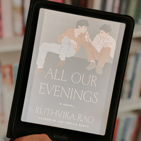 A brown hand holding up an iPad with the cover of ALL OUR EVENINGS.