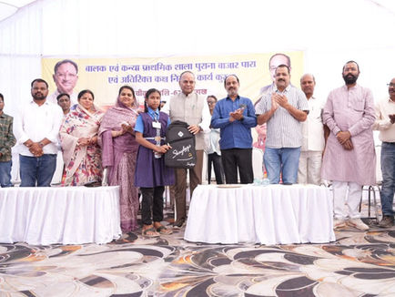 Ajay Chandrakar Kurud distributing school bags to students during Purana Bazar Para school bhumi pujan ceremony