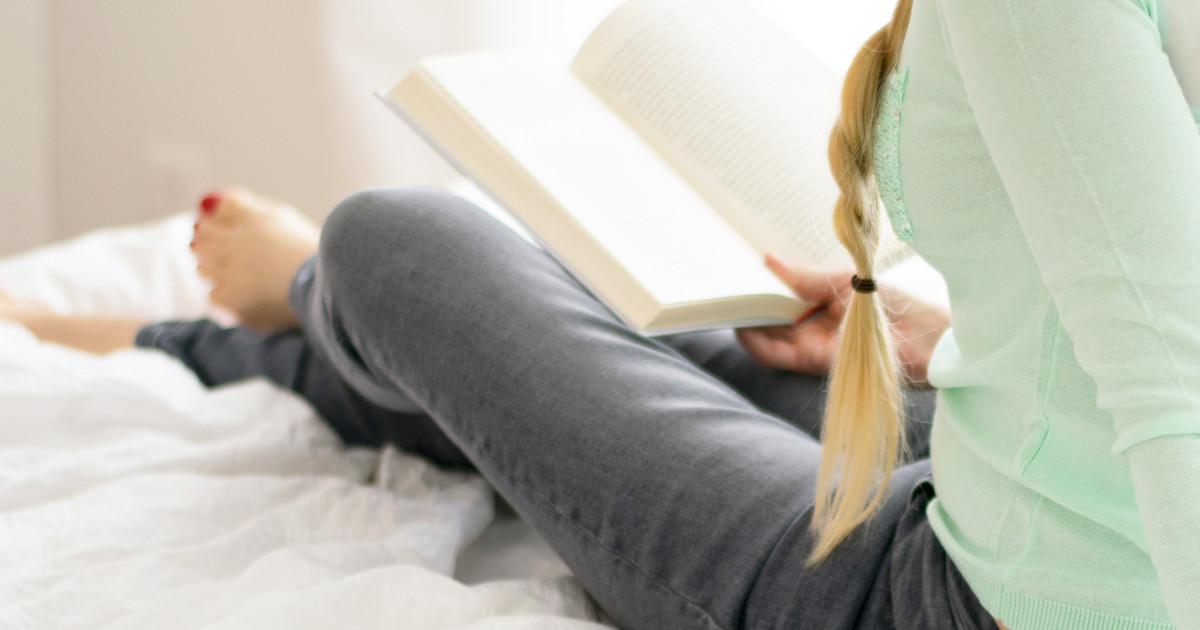 A person following a calming bedtime routine, including reading and dim lighting, to support healthy sleep habits.