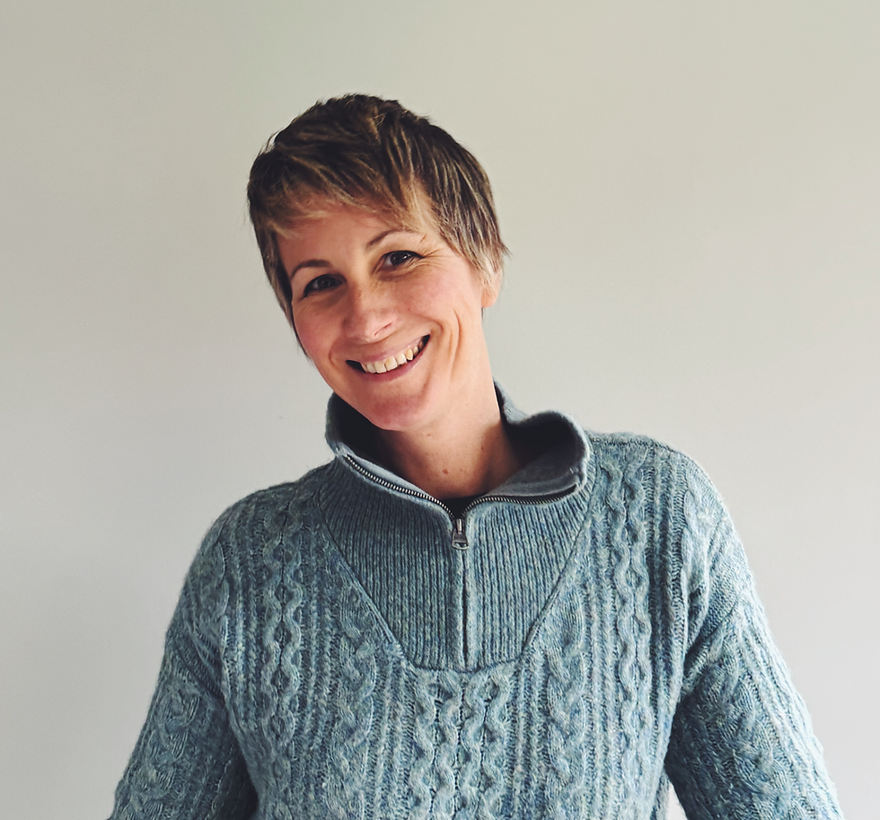 Aimee from Sensitive and Queer, smiling and wearing a blue knitted jumper, representing supportive queer spaces for highly sensitive people.