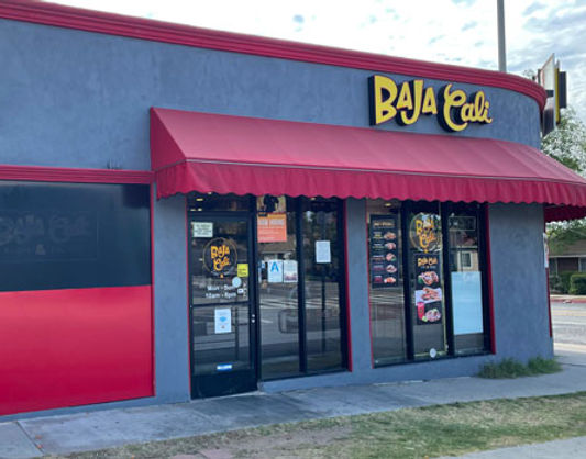 Exterior of the Baja Cali Fish & Tacos Washington Blvd location in Pasadena, featuring a gray storefront, red awning, front entrance, and Baja Cali signage.