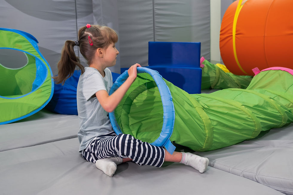 Child girl in roller tonnel during sensory integration session child with physiotherapist