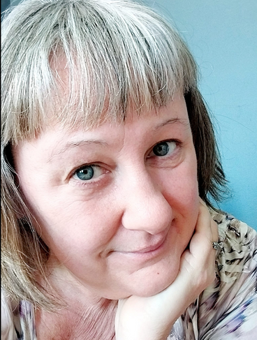Older woman with silvering hair and big blue eyes.