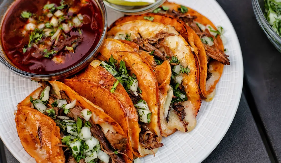 Um prato com Tacos de Birria recheados e um pote com o caldo de carne