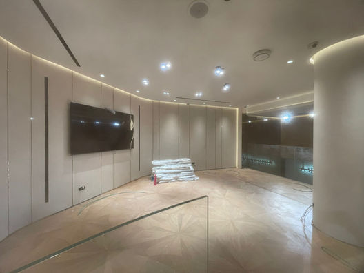 Modern interior with TV, wooden floor, and stacked items on display. Wind Royal SL