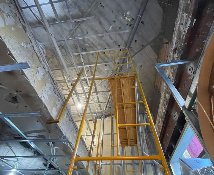 Yellow scaffold in construction site, working on ceiling renovation and repair overview