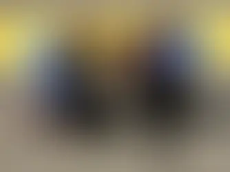 Athlete in a wheelchair racer, flanked by four supporters wearing blue MR8 shirts, posing on Boston Marathon finish line. Smiling, joyful scene.