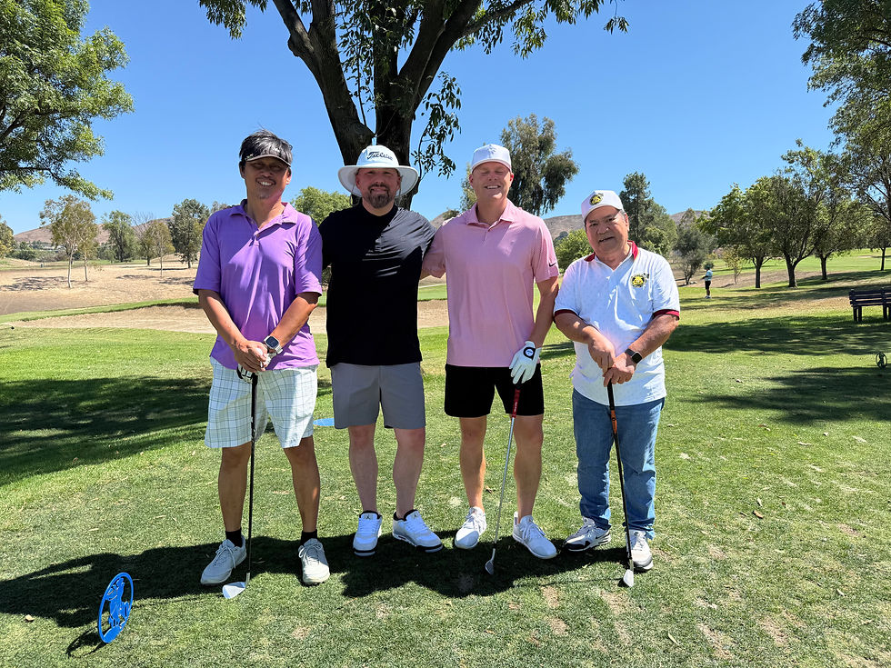 Eye-level view of golfers smiling beside carts on a fairway during a charity tournament.