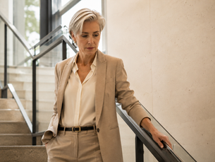 A woman in on a staircase with her hand on railing reflecting on a meeting