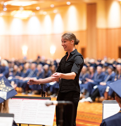Orchestra teacher with graduates in the background