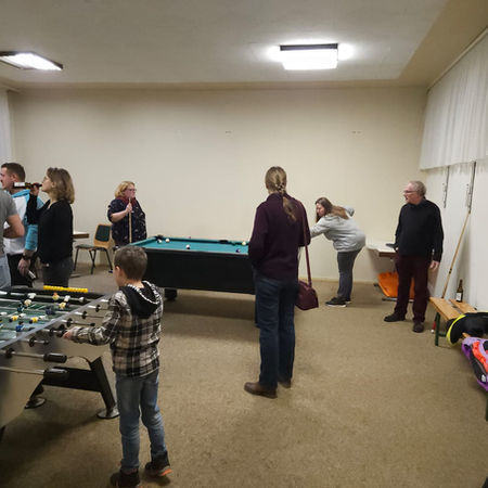 Zwei Kinder spielen Kicker und vier Erwachsene wechseln sich bei einer Partie Billard ab.