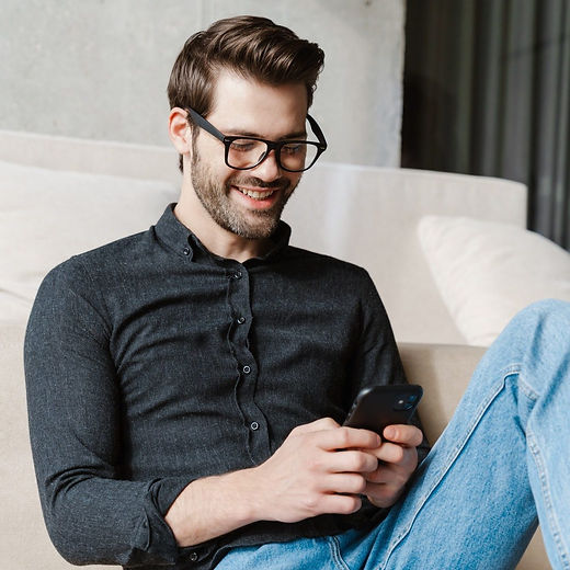 cheerful-unshaven-man-using-smartphone-while-sitting-on-floor-e1630980321404.jpg