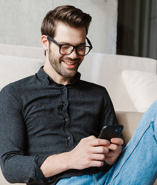 cheerful-unshaven-man-using-smartphone-while-sitting-on-floor-e1630980321404.jpg