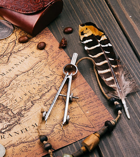 feather-compasses-coffee-beans-coins-lie-old-yellow-map.jpg