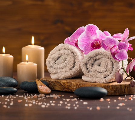 spa-setting-with-brown-rolled-towel-orchids-candles-wood.jpg
