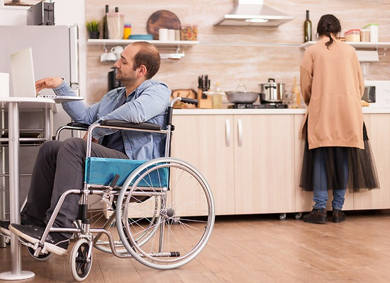 guy-with-walking-disability-wheelchair-using-laptop-kitchen-wife-is-cooking-meal-disabled-