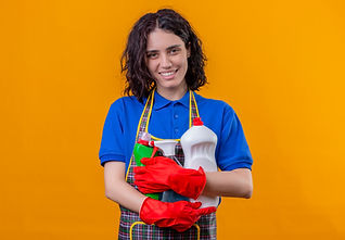 young-woman-wearing-apron-rubber-gloves-holding-cleaning-supplies-looking-camera-positive-