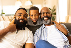 smiling_family_sitting_couch_child_hugging_two_adults_enjoying_time