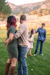 A mother and father watch their children play at sunset Copyright Valerie Bernal Portraits