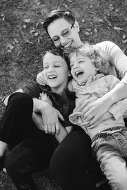 A mother and her two sons roll in the grass laughing copyright Valerie Bernal