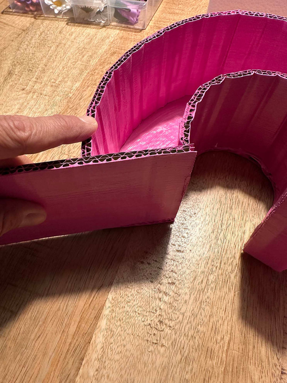 Zahl Drei wird gebastelt aus angemalter, pinker Wellpappe