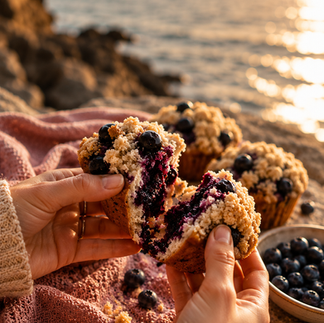 Muffins aux myrtilles et crumble dégustés au bord de la mer au coucher du soleil, avec un muffin ouvert laissant apparaître un cœur fruité et fondant.