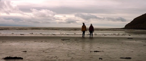 Two women walk in the distance on a wintery beach