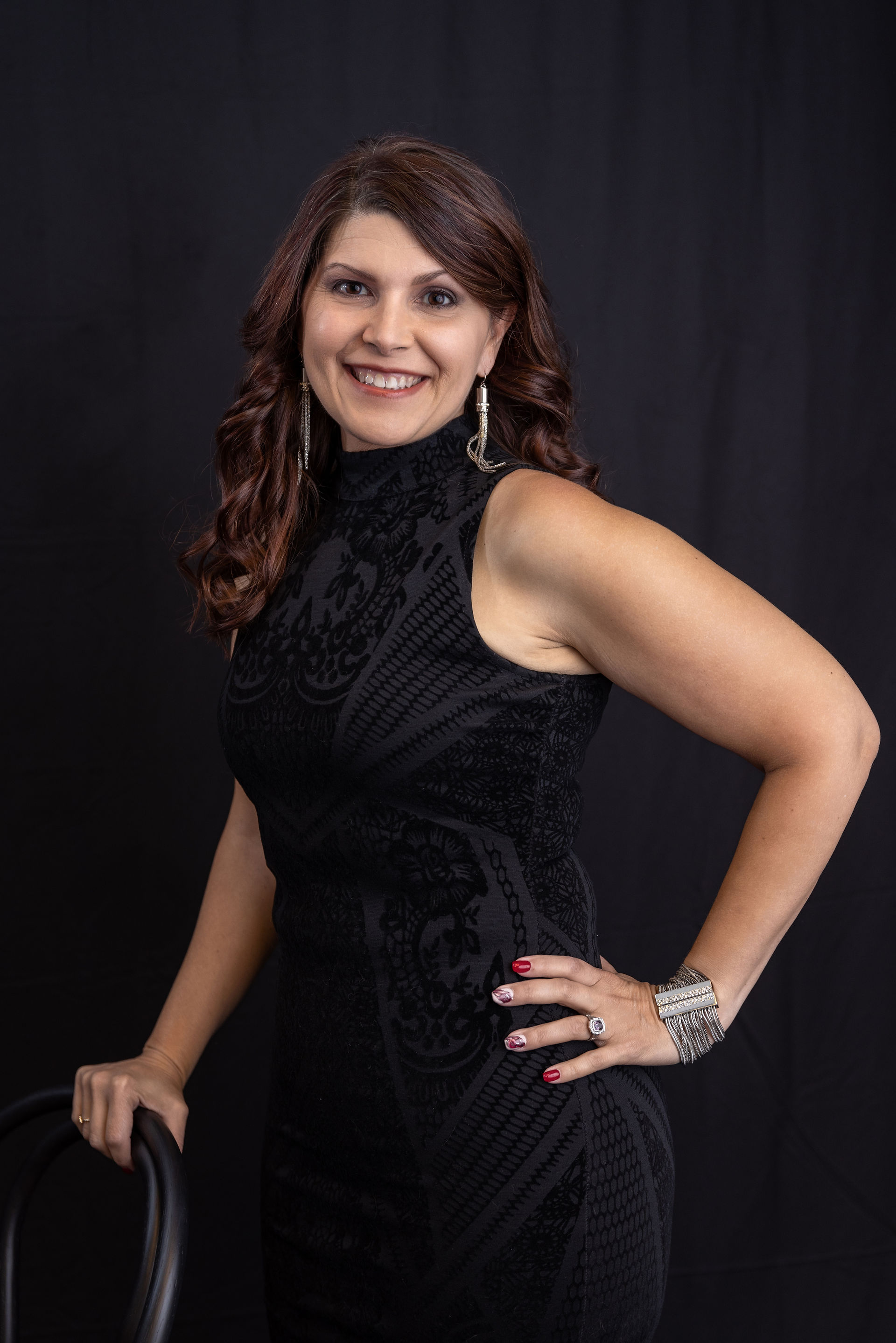 Brown haired woman in a sleeveless black dress for her headshot photo