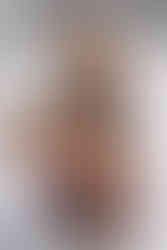 Tattooed woman on white bed in black lingerie