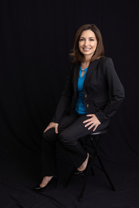 Full body headshot of woman in black pants and jacket and blue top