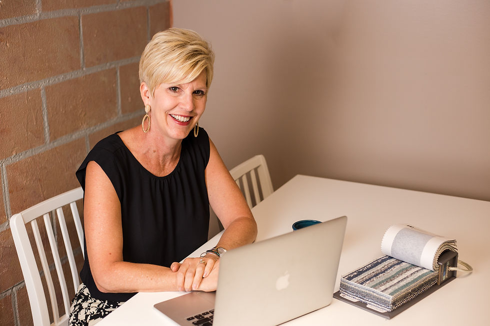 Blonde woman in sleeveless black shirt with fabric swatches and laptop