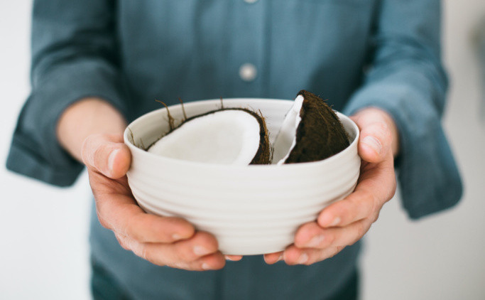 A person holding a bowl of coconuts.