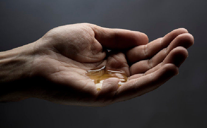 A hand holding a small amount of facial oil.