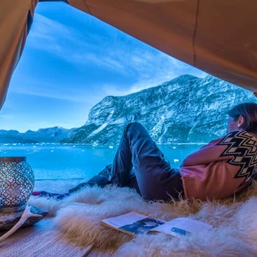 A woman sitting in her tent, gazing at the beautiful lake