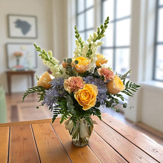 A vase of yellow, pink, blue and white flowers