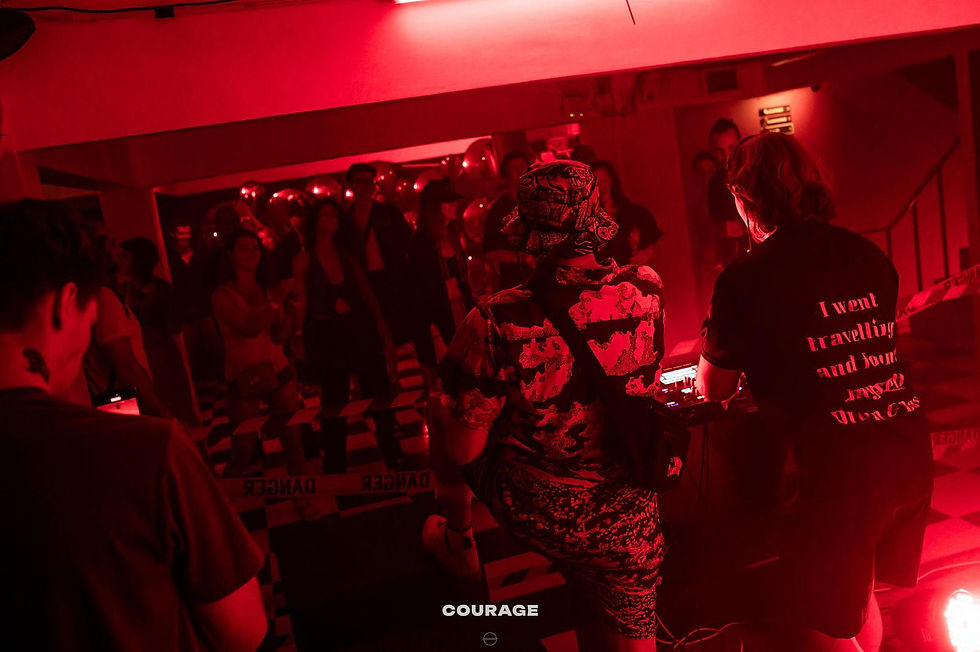 DJ Lindz plays at "Sub Phuket presents Stanton Warriors" event at Courage Bar, Phuket — packed dance floor bathed in red light with the DJ wearing a DnB Thailand Branded T-shirt