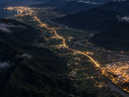 從高處俯瞰花蓮到台東台9線縱谷公路的夜間景色,花蓮市區燈火與台東市區燈火之間的車流光軌貫穿山脈