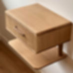 A minimalist white oak floating nightstand featuring a contrasting custom black walnut drawer pull.