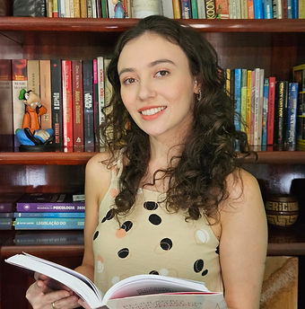 mulher de cabelos ondulados e olhos castanhos segurando um livro