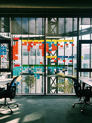 Glass wall with what could be a program board for agile, risk tracking, kanban or other style of board using sticky notes.