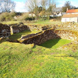 Foundations of castle towers with houses in background