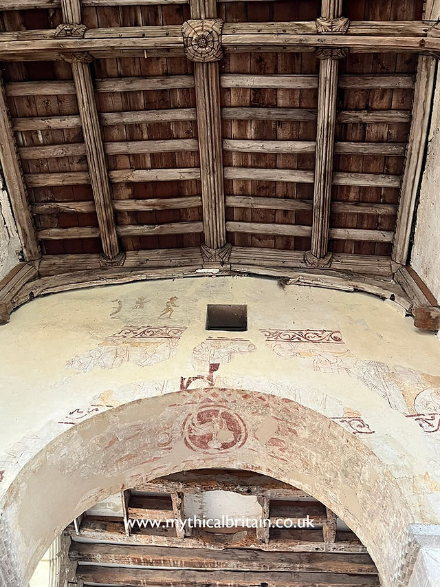 view looking up towards wall paintings on the chancel arch showing the lamb of God, as well as a view of the fifteenth century roof at Duxford St John's