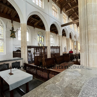 A view into the nave of a church, showing decorated benches, richly carved roof and fifteenth century pillars
