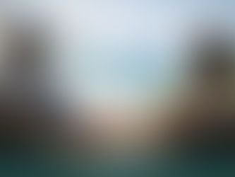 casal sentado em uma varanda à beira-mar, de mãos dadas e contemplando o mar calmo ao fundo